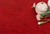 A close-up of pink carnations and a vase on a red carpet. Produktbild-Vorschau