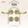 A marketing image showcasing a set of bronze-colored door handles and rosettes against a light beige and white patterned background, with a house-like outline and text. Produktbild-Vorschau