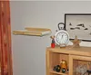 A wall-mounted cat bed is shown on a wall above a wooden cabinet with decorative items. Produktbild-Vorschau