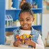 A young girl is holding action figures in front of a bookshelf. Podgląd zdjęcia produktu