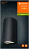A dark gray background with a black wall lamp in the foreground. The packaging is visible on the right side of the image. Voir les images du produit