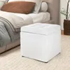 A white storage ottoman is placed next to a bed with pillows and blankets. Podgląd zdjęcia produktu