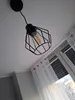 A black industrial-style pendant light fixture with a filament bulb hangs from a white ceiling. Produktbild-Vorschau