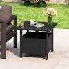 An outdoor side table with a drink and magazines on top, placed on a patio next to a chair, with a lawn and flowers in the background. Podgląd zdjęcia produktu