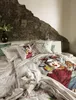 A bedroom scene with a bed featuring bedding with a Frida Kahlo print. Produktbild-Vorschau