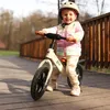 A young child is riding a balance bike on a wooden bridge outdoors. Náhled obrázku produktu