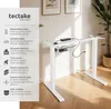 A white electric standing desk frame is shown in a room with light-colored walls and flooring. To the left is a panel with text and icons describing the product's features. Náhled obrázku produktu