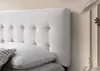 A close-up of a white tufted headboard and a pillow on a bed. Náhľad obrázku produktu