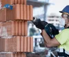 A construction worker is using a reciprocating saw to cut through a brick wall. Voir les images du produit