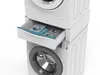 A stacked washing machine and dryer unit with a drawer pulled out, containing laundry detergent pods. Voir les images du produit