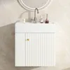 A white bathroom vanity with a fluted door and a gold handle, with a faucet and some toiletries on top. Voir les images du produit