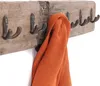 A close-up view of a wooden coat rack with metal hooks, one of which is holding an orange scarf. Náhled obrázku produktu