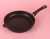 A black frying pan with a black handle is placed on a pink background. Náhľad obrázku produktu