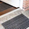 A doormat is placed on a stone patio in front of a doorway. Produktbild-Vorschau