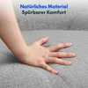 A hand pressing into a soft, grey fabric surface, likely a sofa or armchair. Produktbild-Vorschau