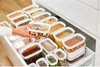 A hand is reaching into a drawer filled with various food storage containers. Voir les images du produit