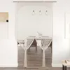 A macrame curtain hanging in a doorway, with a dining area visible through it. Produktbild-Vorschau