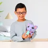 A young boy is playing with a purple elephant toy, feeding it with a green bottle. Anteprima dell’immagine prodotto