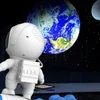 A cartoon astronaut looking at Earth and the Moon in space. Náhled obrázku produktu