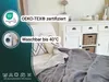 A bed with a folded blanket, pillows, and a white dresser in the background. Produktbild-Vorschau
