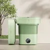 A light green, foldable mini washing machine is shown outdoors next to a tree. Náhled obrázku produktu