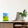 A framed picture of a landscape is displayed on a wooden shelf next to decorative items. Anteprima dell’immagine prodotto