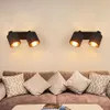 Two black wall lights with gold interiors are mounted on a wall above a sofa with several cushions. Voir les images du produit