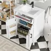 A white bathroom vanity with a sink and open doors, showing storage shelves and bottles. Podgląd zdjęcia produktu