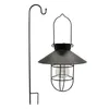 A black solar lantern with a warm white Edison bulb hangs from a black shepherd's hook, both against a white background. Produktbild-Vorschau