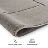 Close-up of a gray bath mat with text and icons below. Náhled obrázku produktu