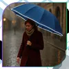 A woman walks in the rain holding a blue umbrella. Náhled obrázku produktu