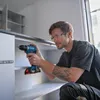 A man is using a cordless drill to assemble a cabinet. Voir les images du produit
