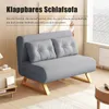 A gray sofa bed with gold legs is shown in a living room setting, with a side table and a coffee table visible. Náhľad obrázku produktu