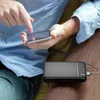 A person is holding a smartphone and a power bank is on their lap. Produktbild-Vorschau
