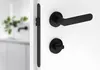 A black door handle and lock set on a white door. Produktbild-Vorschau