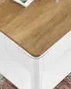 Close-up view of a corner of a white coffee table with a wood-look top. Náhled obrázku produktu
