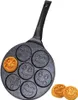 A frying pan with seven emoji-shaped molds, with one mold containing a cooked pancake and two cooked pancakes placed next to the pan. Produktbild-Vorschau