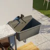 An outdoor sink mounted on a wall next to a countertop, with a tiled floor and grass in the background. Produktbild-Vorschau