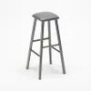 A gray metal industrial stool with a faux leather seat is shown against a white background. Voir les images du produit