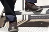 A person wearing work pants and safety shoes is walking up a set of metal stairs. Produktbild-Vorschau