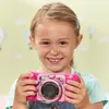 A young girl is holding a pink VTech Kidizoom Duo Pro camera. Produktbild-Vorschau