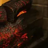 A close-up view of artificial logs with glowing red embers, suggesting a fireplace. Produktbild-Vorschau