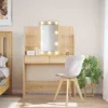 A well-lit bedroom scene featuring a wooden vanity table with a lighted mirror, a chair, and a potted plant. Náhľad obrázku produktu
