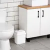 A bathroom scene with a toilet, a white trash can, and a white cabinet with a wooden countertop. Produktbild-Vorschau