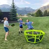 A family playing paddle ball in a grassy yard with mountains in the background. Produktbild-Vorschau