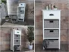 Collage of images showing a white storage cabinet with gray woven baskets against a wood-paneled wall. Anteprima dell’immagine prodotto
