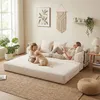 A woman and a child are relaxing on a large, modular sofa bed in a bright, airy living room. A puppy is playing with the child. Anteprima dell’immagine prodotto