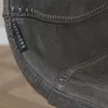A close-up of a dark gray bar stool with visible stitching and a brand tag. Produktbild-Vorschau