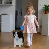 A young girl walks a toy dog indoors. Anteprima dell’immagine prodotto