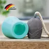 A close-up of two silicone molding components, one turquoise and one gray, resting on a wooden surface. A rope is attached to the gray component. Produktbild-Vorschau